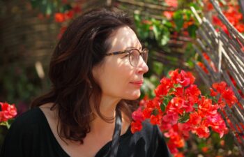middle aged woman sniffing a tropical flowers in the garden